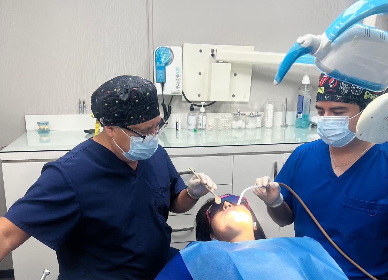Cirugía dental en Tijuana: cirujano dentista y asistente atendiendo a una paciente