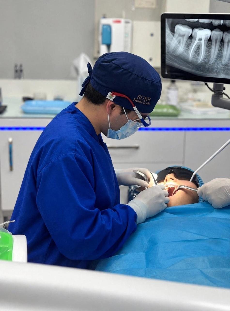 Endodoncia en Tijuana: dentista de Sure Dental realizando un tratamiento de conductos con la radiografía en el monitor